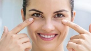 一个女人微笑着指着她健康的眼睛