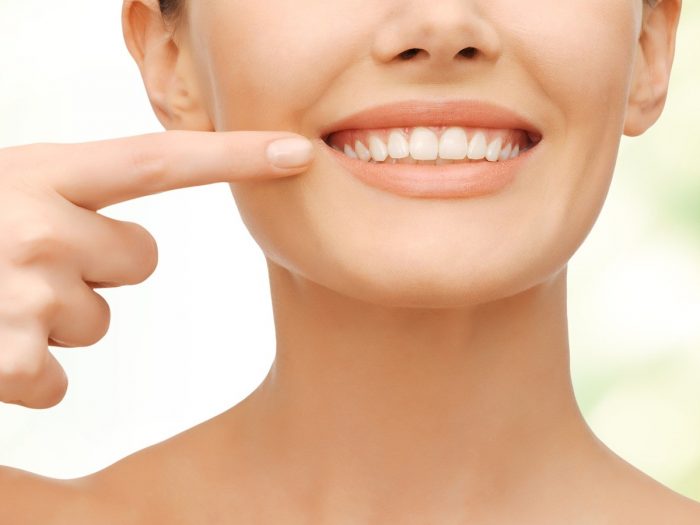 关闭了一个女人微笑着指着她的牙齿拍