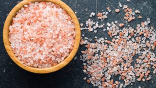 粉红色的喜马拉雅盐在黑色背景的碗内外