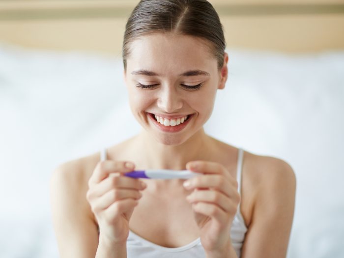一个微笑的女人在做家庭早孕测试