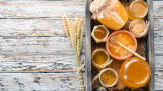 蜜罐瓶和碗的开销镜头在托盘上的木柜台