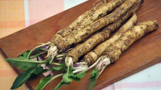 新鲜的山葵和叶子放在木制砧板上