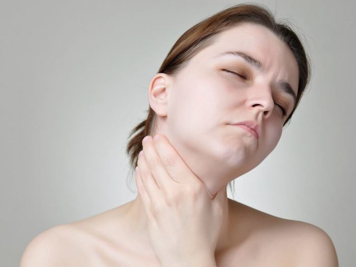 一位年轻女子拿着从她的甲亢痛苦的喉咙痛苦