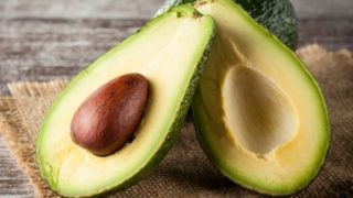 一个半个鳄梨的特写镜头,把整个鳄梨放在粗麻布上