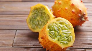 新鲜的整个特写镜头和一半的kiwano果子在一张木桌上