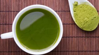 一杯充满茶的杯子伴随着一勺克拉特马粉