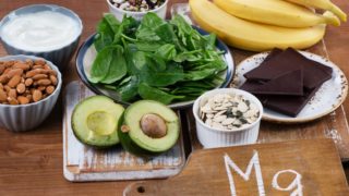 把杏仁、香蕉、豆类、菠菜、黑巧克力和鳄梨等富含镁的食物放在木桌上