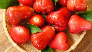 鲜红的马来苹果放在一个圆形的藤盘里