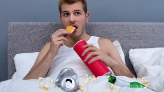 男人一边看电视一边吃薯片