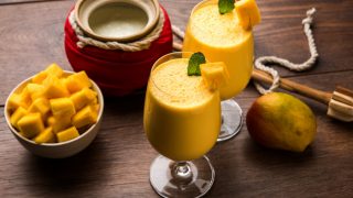 芒果Lassi的特写镜头或冰沙与豆腐,切水果块和搅拌器大眼镜