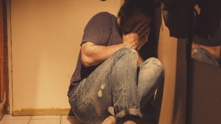 患有急性抑郁症和创伤后应激障碍的男子恐惧地坐在角落里
