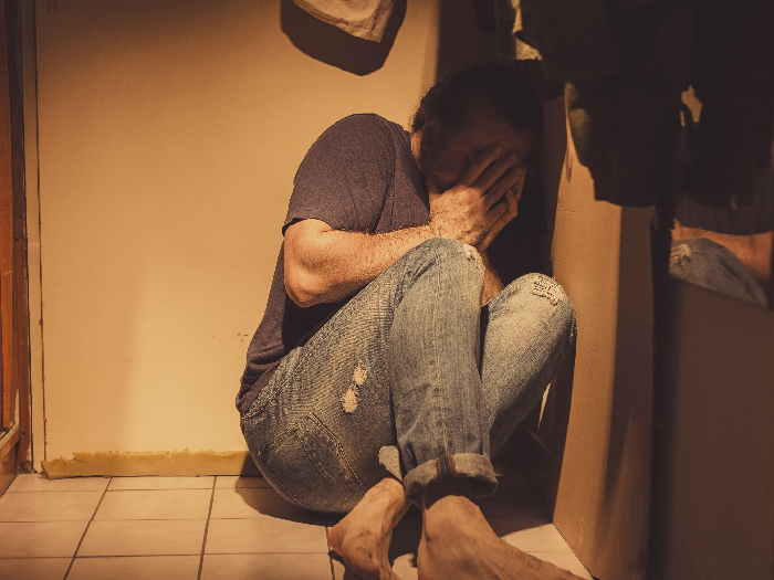 男子与急性抑郁症和创伤后应激障碍坐在角落与恐惧