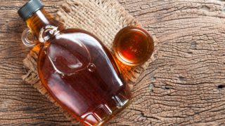 放在黄麻布上的小玻璃杯和瓶子里的枫糖浆