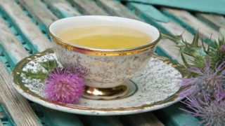 蓝色的木桌上放着一杯水飞蓟花茶