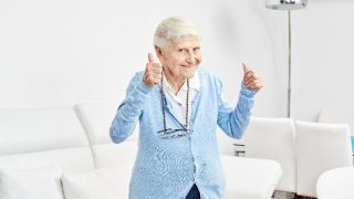 一个老妇持有竖起大拇指充满幸福和兴奋