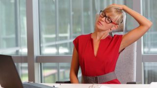 红色礼服的女子坐在她的办公桌伸展脖子