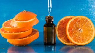 甜橙精油,滴管和橙片的蓝色背景上的一瓶