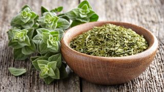 新鲜的牛至香草和木桌上的干牛至木碗