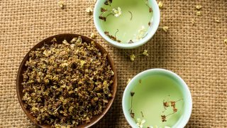 平面视图两碗水上面有桂花和一大碗桂花在粗麻布上。