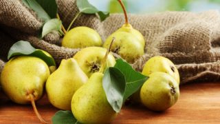 木桌上放着一袋新鲜成熟的绿色梨子