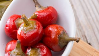 在木制的厨房顶上,用白色的碗煮熟的pimentos