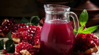 一个罐子充满石榴汁和新鲜的石榴珍珠在一张木桌上