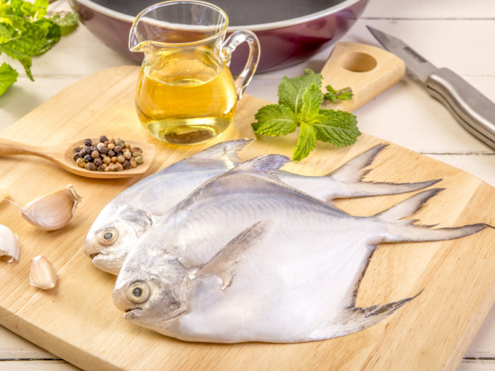 在一个木切板的Pompano鱼有油瓶和香料在背景中