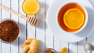 茶,不同的树叶,蜂蜜,柠檬生姜和红糖白色木制桌子背景杯