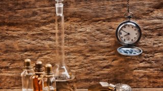 一瓶瓶的玫瑰木油和一个高瓶和古董钟挂着