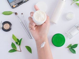 skincarecream 一只手拿着一小盒奶油,背景是白色的