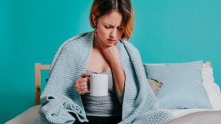 喉咙痛的女人正在喝热饮西甲买球 万博