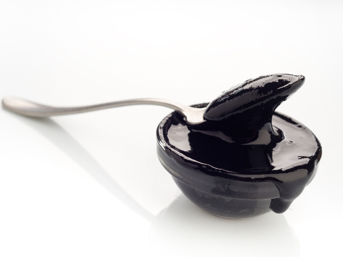 勺子与浓缩糊状墨鱼油墨在白色背景