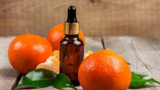 小滴管瓶橘子油,其整体减半橙子和树叶上的木桌