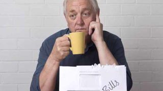 拿着一个黄色杯子的一个老人,看起来与被标记的文件夹被标记为'票据'的文件夹