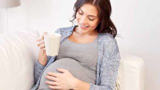 拿着一杯茶的孕妇一只手。