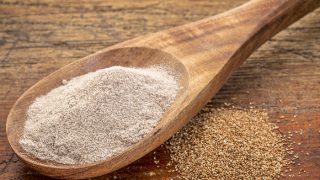 Teff谷物和面粉在木勺中,以木纹为背景