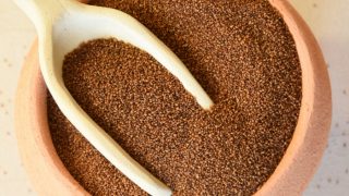 一个土气陶器碗用Teff谷物的手工制造陶瓷瓢在白色背景的