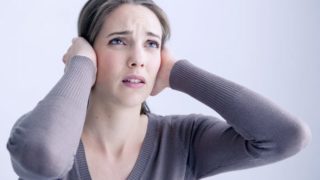 从耳鸣一名年轻女子的痛苦捂住耳朵与她的手