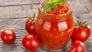 木桌上放着一碗新鲜的番茄罗勒汤,旁边放着番茄