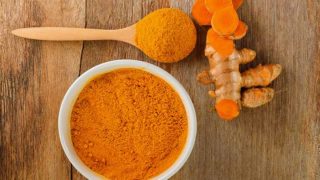 生姜黄根和姜黄粉在一个碗里,用勺子放在木头上