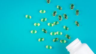 一个打开的白色瓶子,蓝色背景上有黄色的胶囊