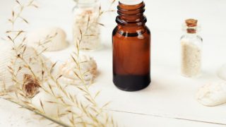 一瓶香根草油与香根草和海盐的小容器在白色背景上