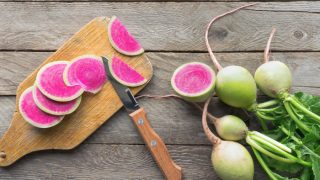 木桌上放有绿叶的切成片的白萝卜。