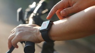 有心率象的妇女骑自行车者手在smartwatch