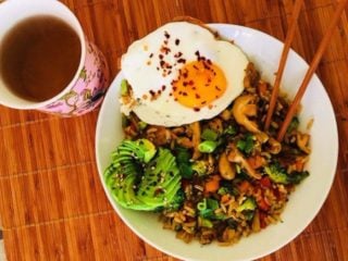 weeknightstirfrywithavocadoandegg 炒菜炒饭,配上牛油果和鸡蛋,放在木桌上