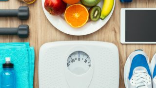 24 Amazing Home Remedies for Weight Loss 节食和减肥保健 - 哑铃,皮尺,帆布鞋,水果,毛巾,奶瓶,白色刻度,与数字平板电脑上一张木桌