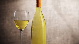 在黑暗的背景下,一瓶和一杯白葡萄酒