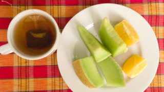 一杯用茶包泡制的红茶,一盘冬瓜片和酸橙放在木桌上