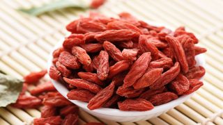 一个白色的碗充满杞子保持在垫子上