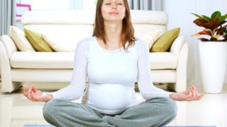 一位美丽的孕妇在客厅里练习瑜伽